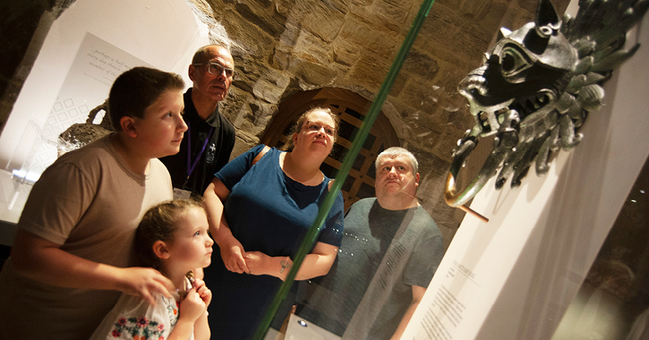 Family with a tour guide stop and admire artefacts on display inside Durham Cathedral Museum